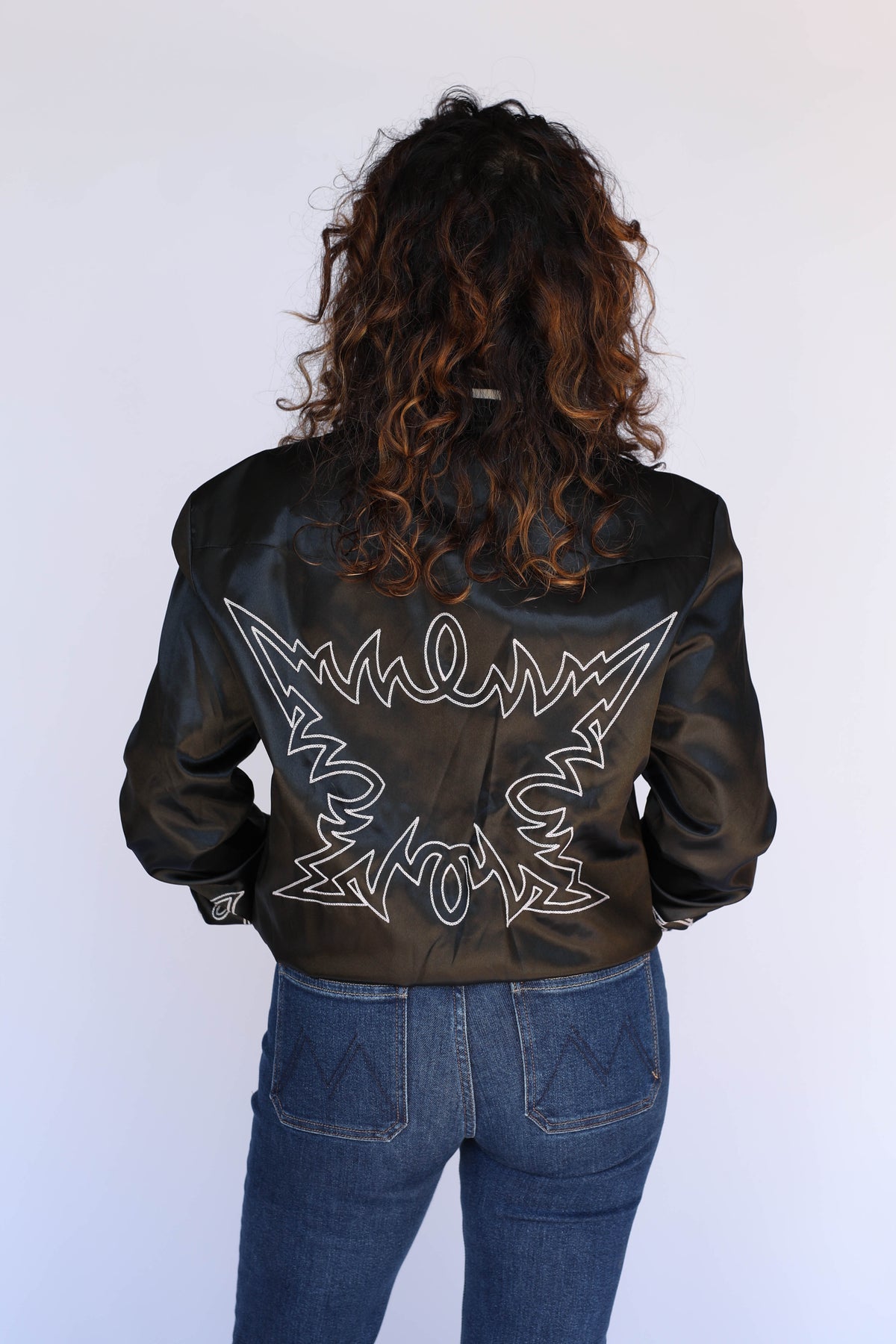 Back view of the H Bar C Odessa black satin tour jacket on a woman, unisex vintage inspired western wear.