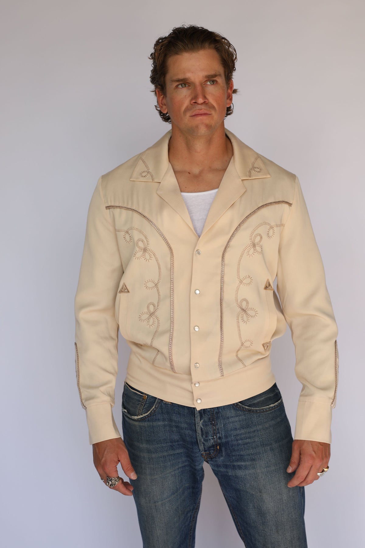 H Bar C Bolero men's beige jacket worn open with jeans and a silver buckle.