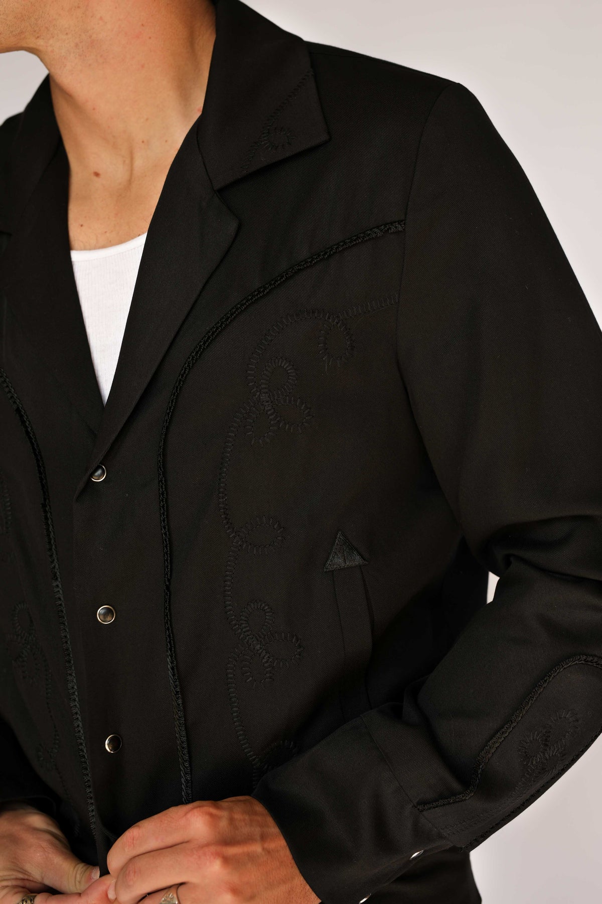 Close-up of the black on black embroidery and snap front on the H Bar C Bolero men's black jacket.