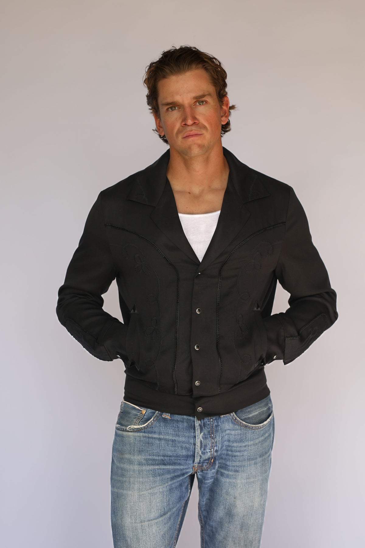 Man with hands in pockets wearing the H Bar C Bolero men's black on black western jacket.