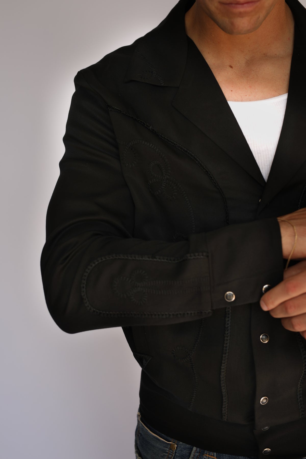 Side detail of the H Bar C Bolero black on black jacket showing tonal embroidery and five button cuff.