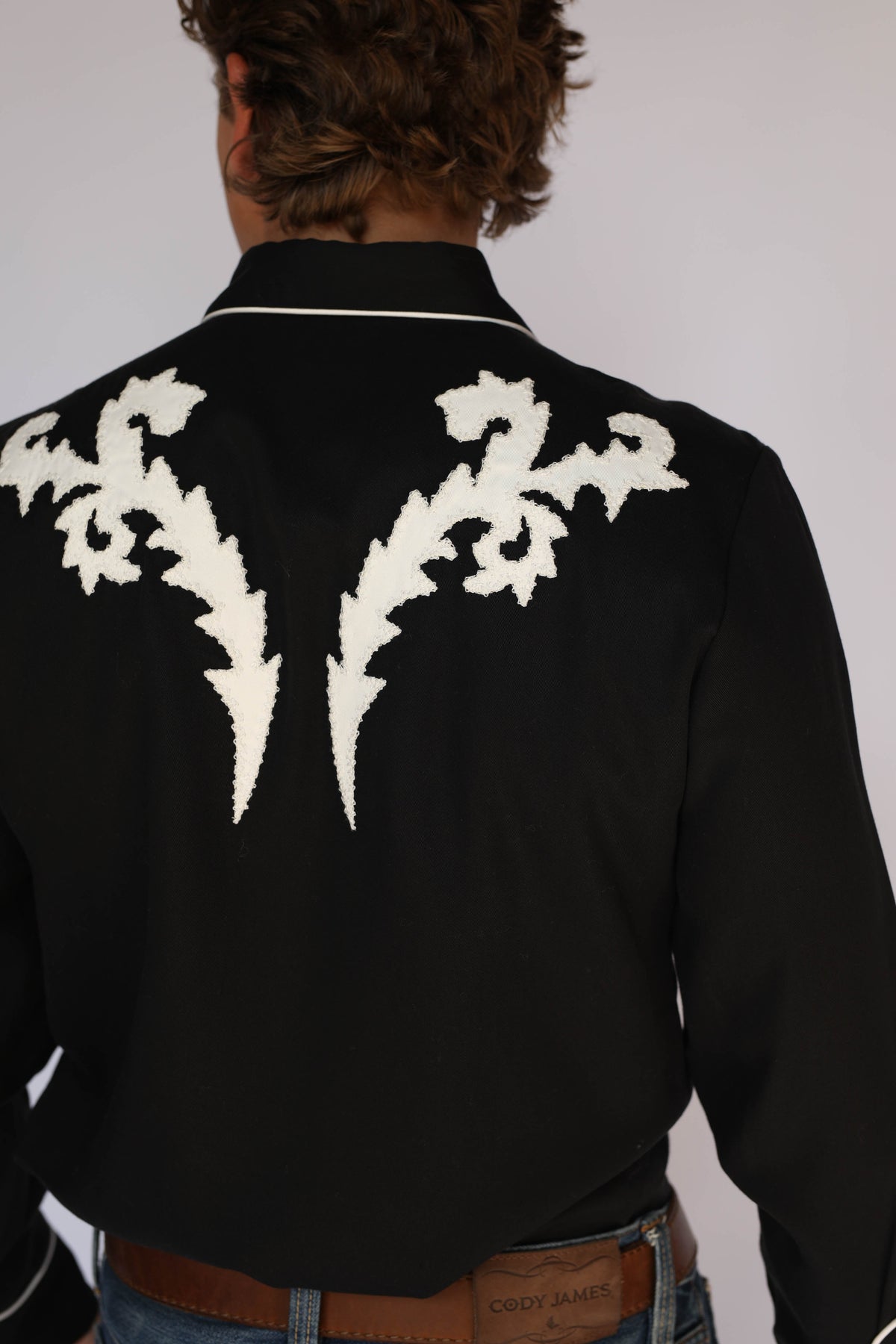 Close-up of the white flame embroidery across the back yoke of the H Bar C Dali black western shirt.