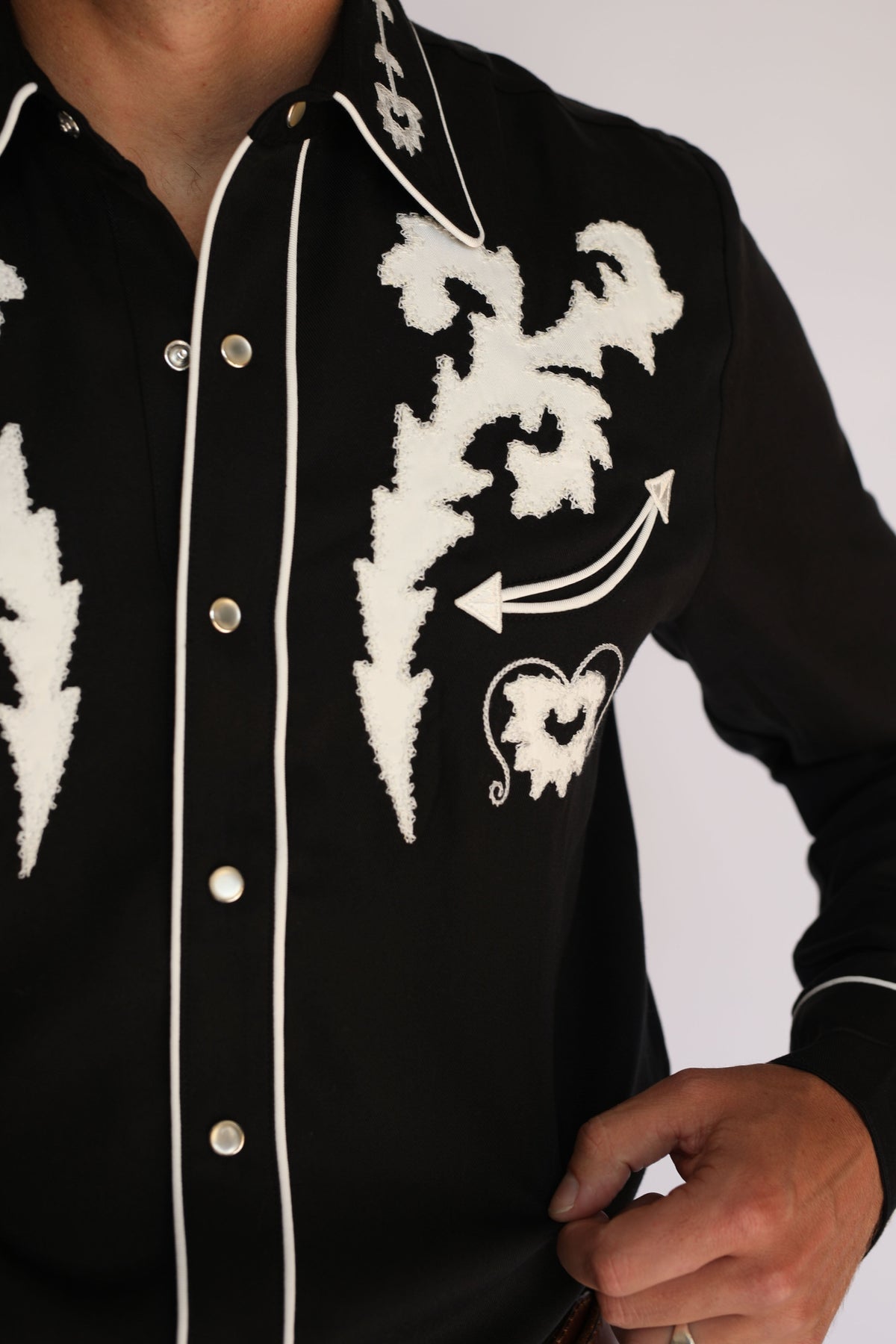 Chest detail of the H Bar C Dali black shirt showing white embroidery, piping, and pearl snaps.