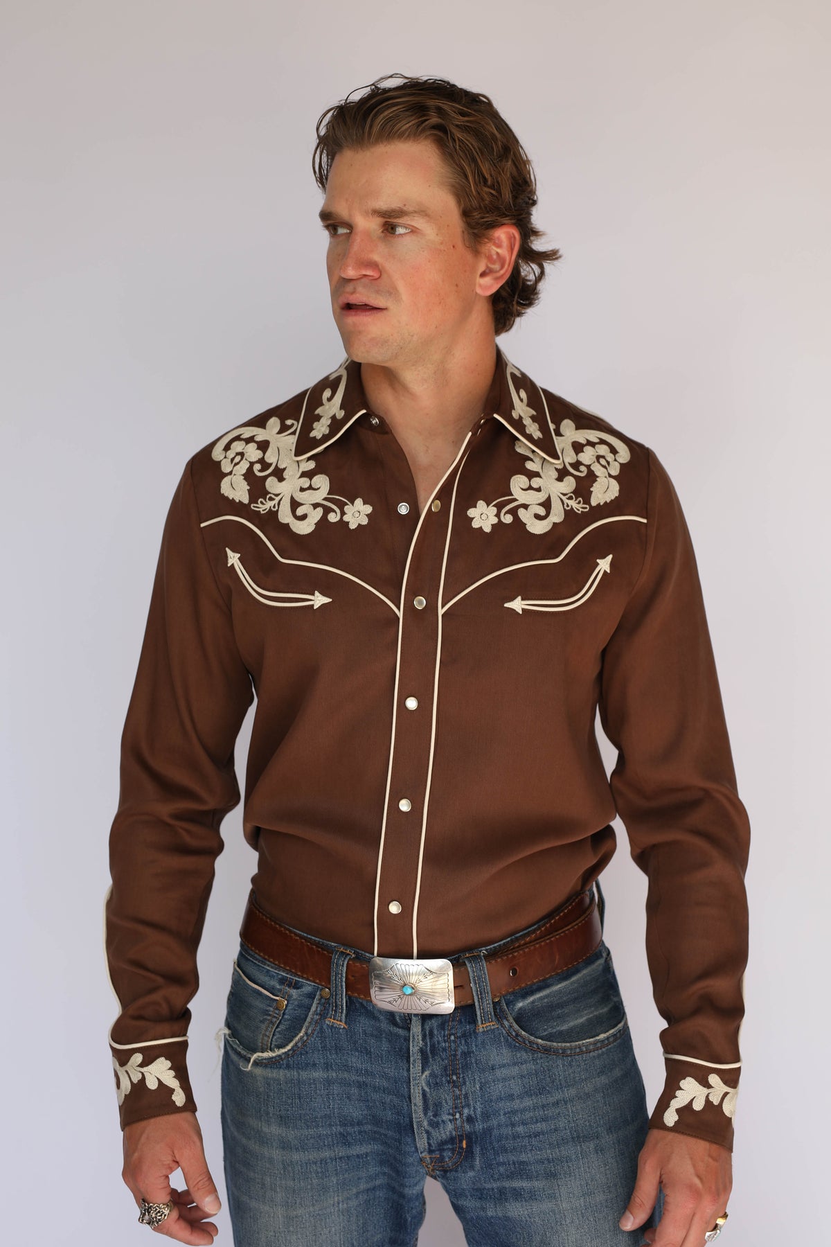 Model in the H Bar C Durango brown Tencel shirt, vintage inspired western wear tucked into blue jeans with a silver belt buckle.