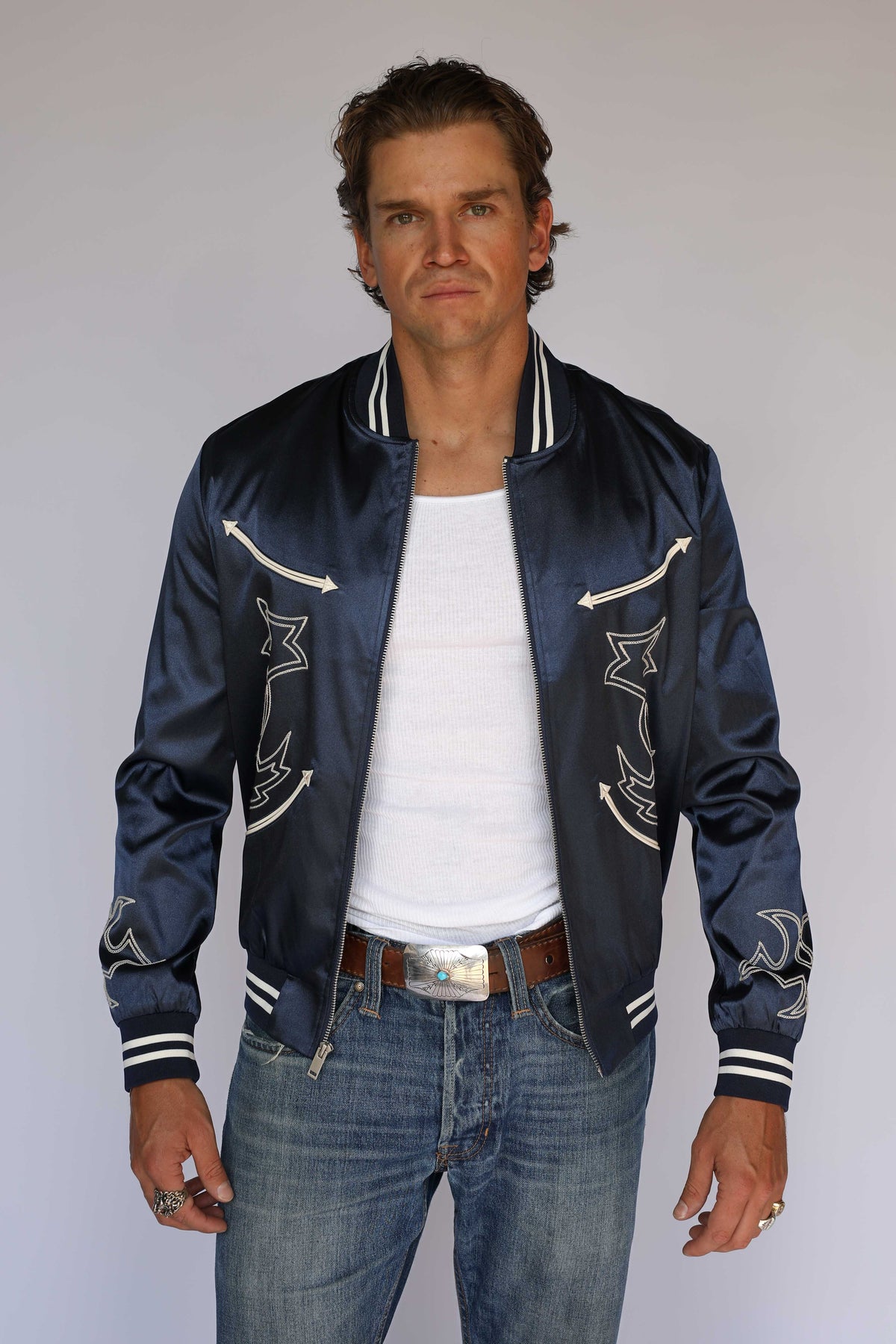 Model in the H Bar C Odessa navy tour jacket with embroidered sleeves and silver buckle, 1950s concert style vintage inspired western wear.