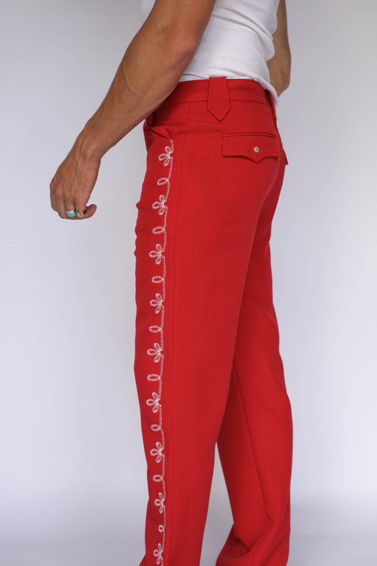 Side view of the H Bar C Bolero pants in red with white floral embroidery down the leg.