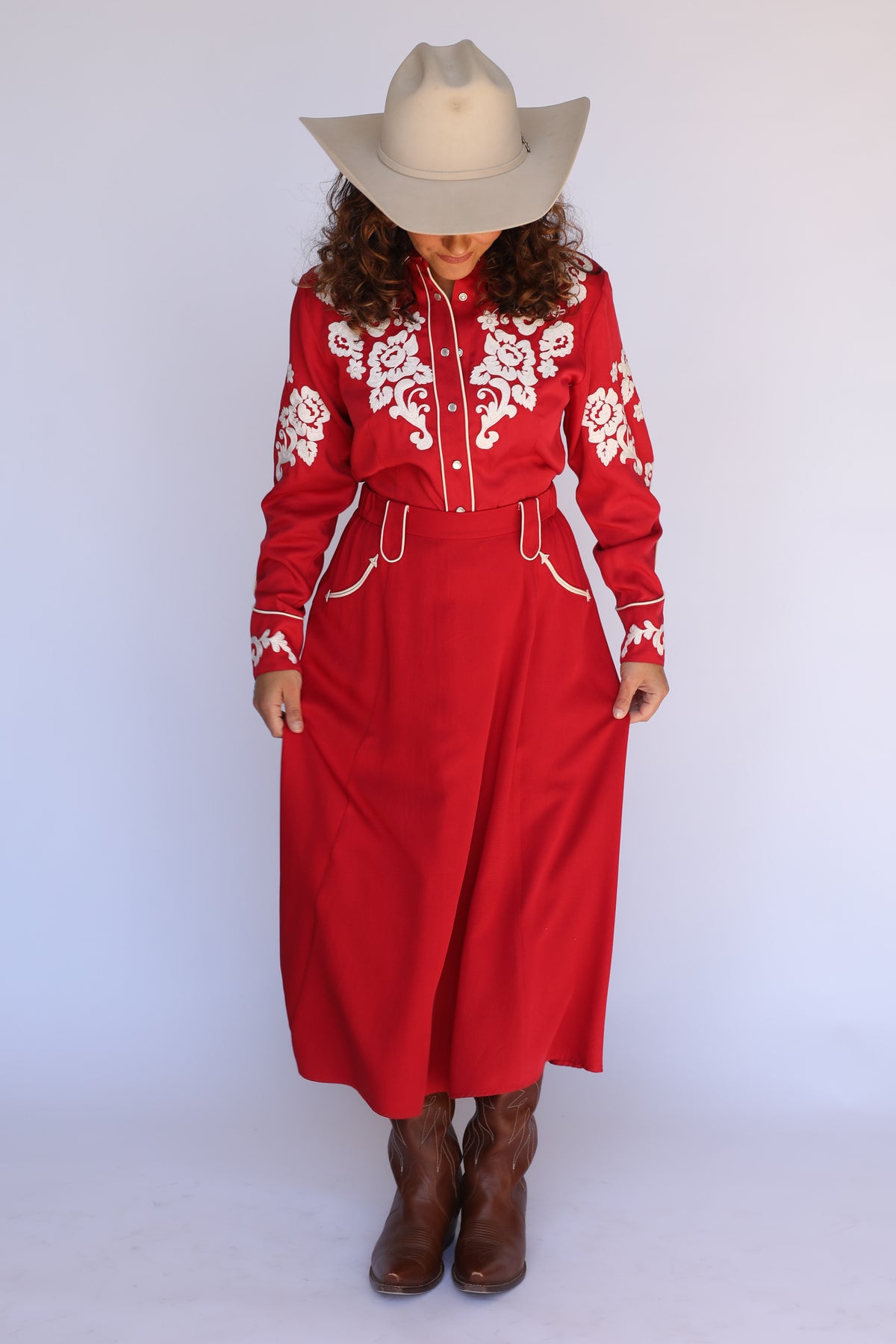 Woman in a cowboy hat wearing the H Bar C Santa Fe red skirt with the Fort Worth red embroidered shirt.