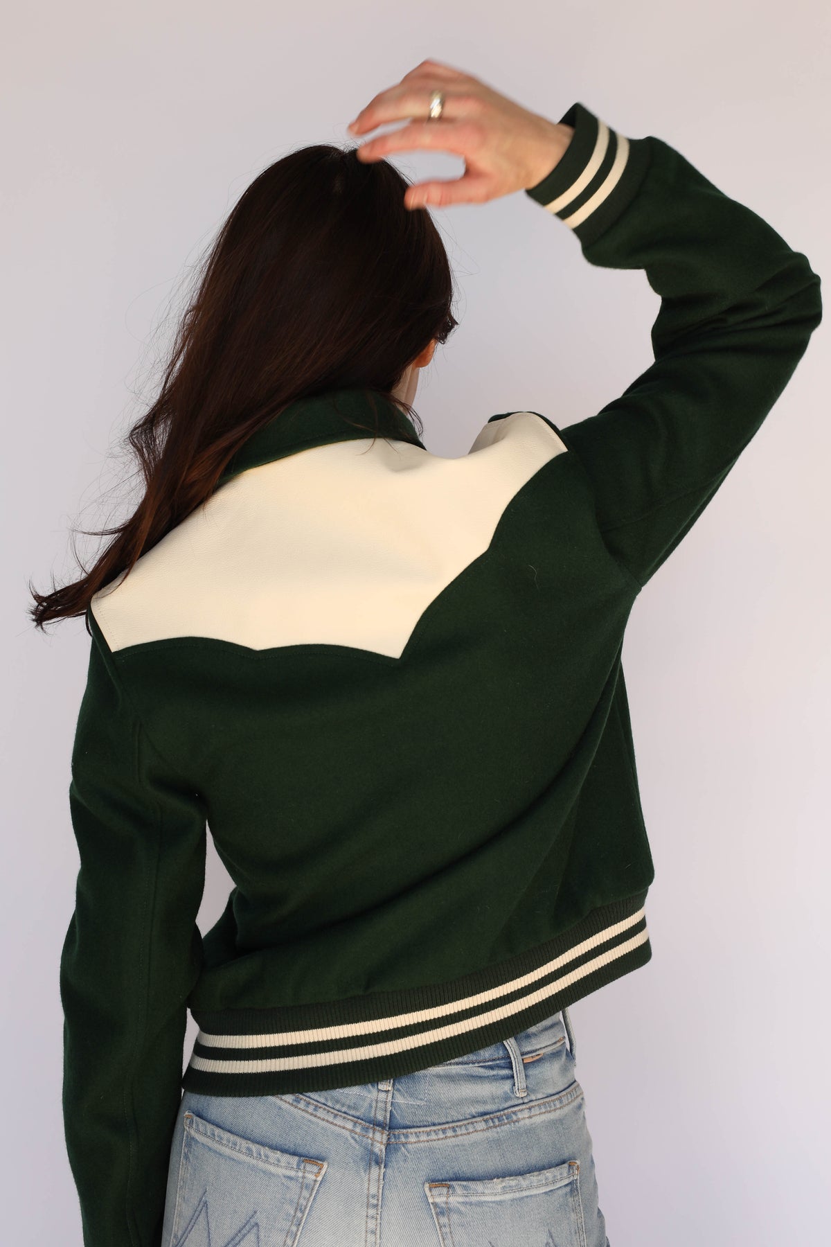 Back view of a woman wearing The Vail H Bar C green jacket with cream back yoke.