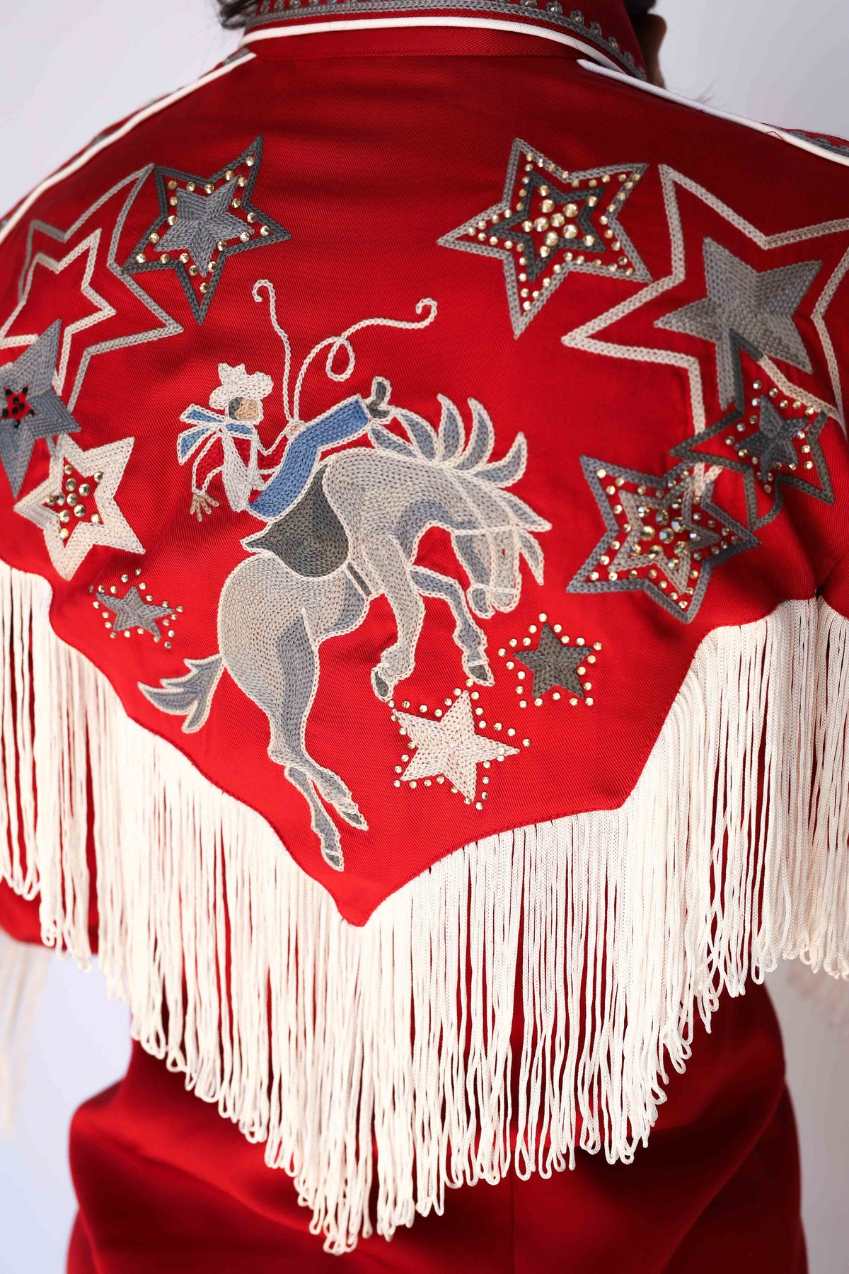 Back of the H Bar C Las Vegas women's red shirt with a chain stitch bucking bronco rider, rhinestone studded stars, and cream fringe yoke, vintage inspired western wear.