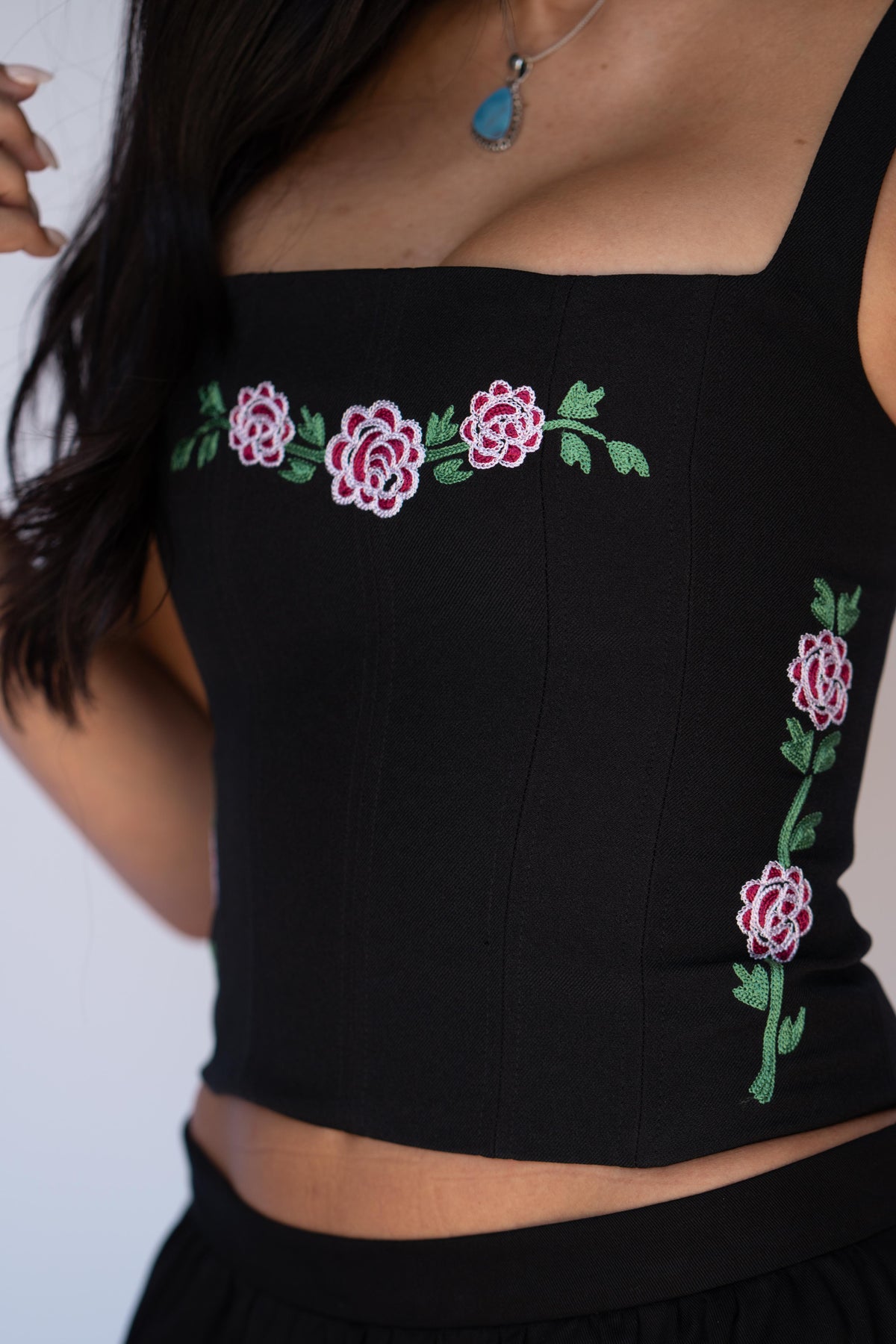 Close-up of the pink chain stitch roses and green leaves on the H Bar C Canterbury black corset top.