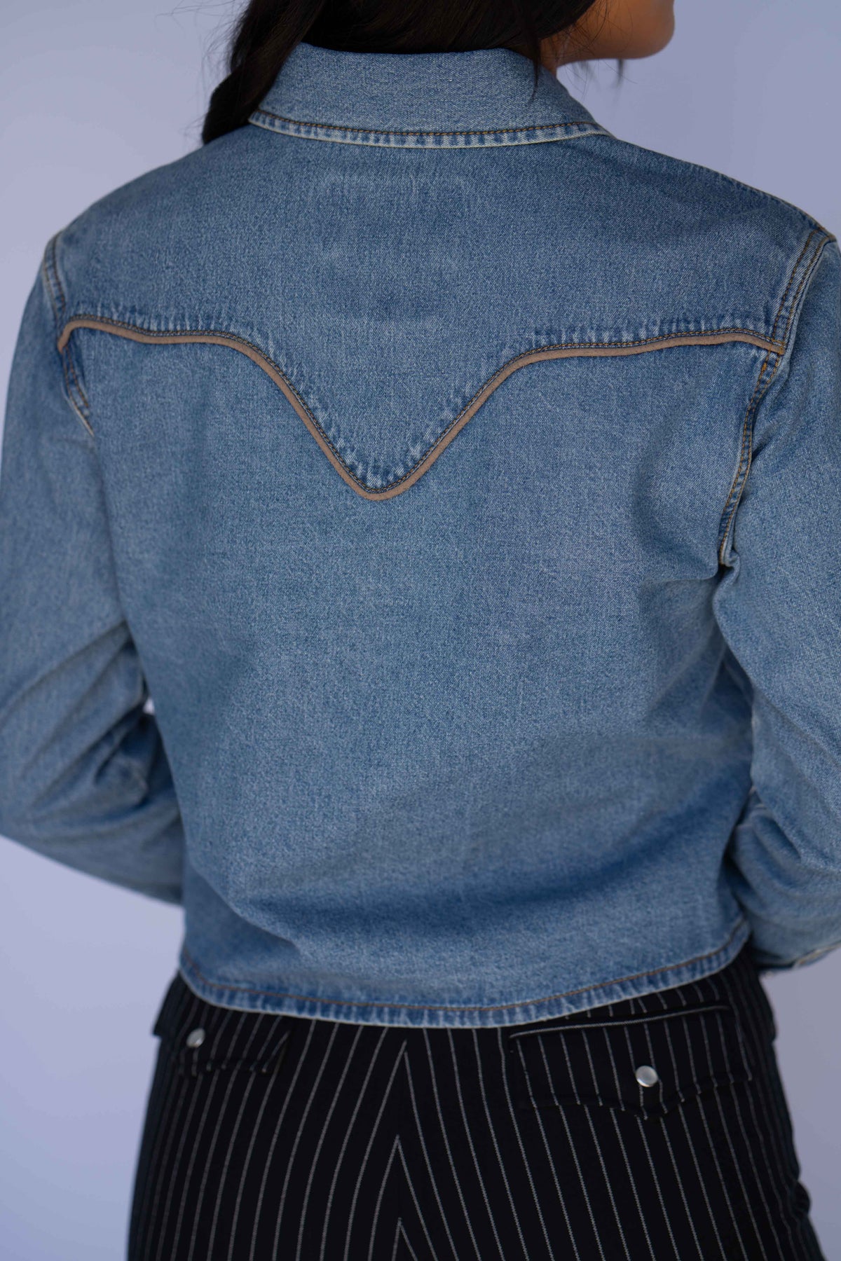 Back yoke detail of the Rustler x H Bar C denim cropped shirt with tan contrast piping.