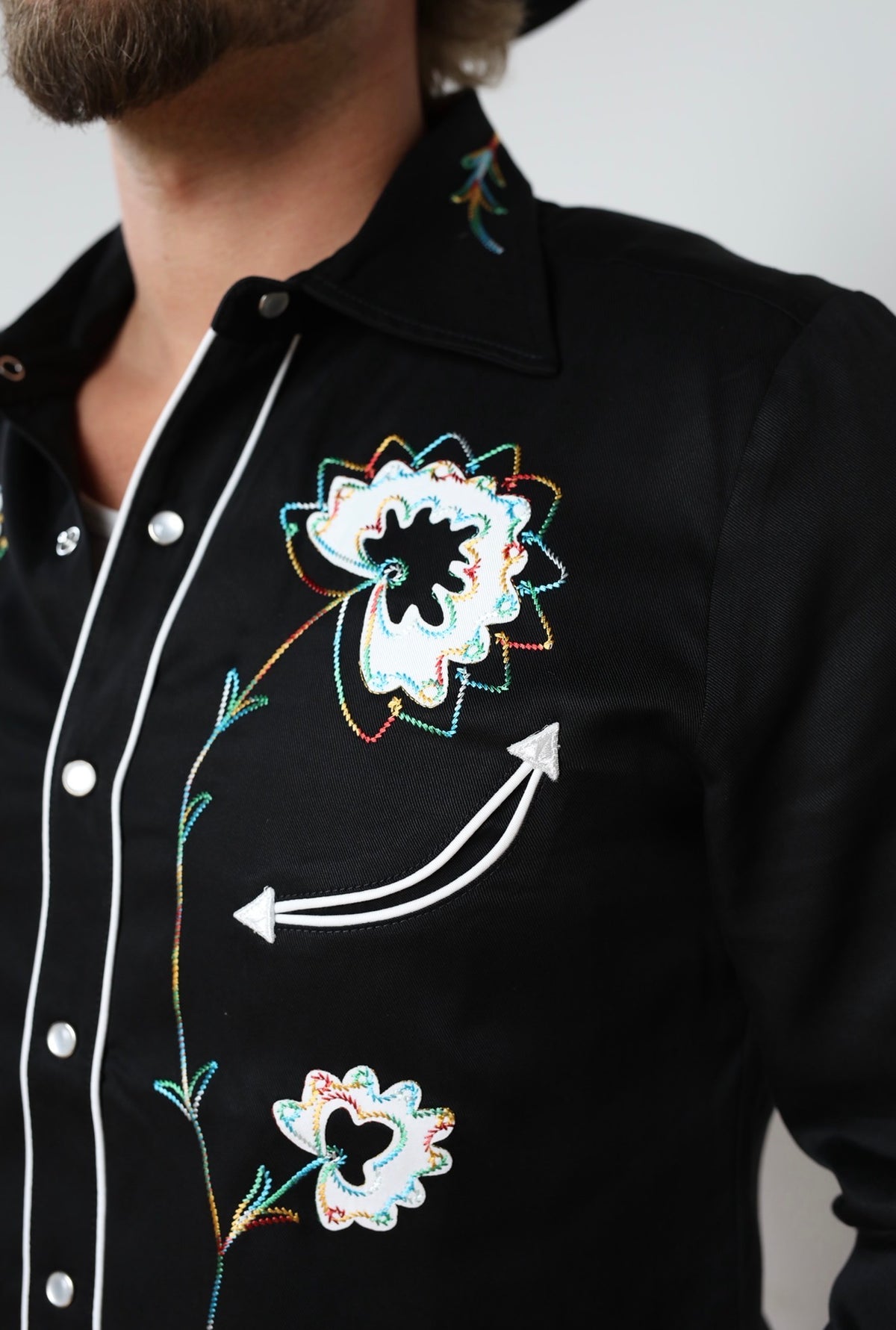 Close-up of the white and turquoise embroidered flowers and arrow on the H Bar C Texas black shirt.