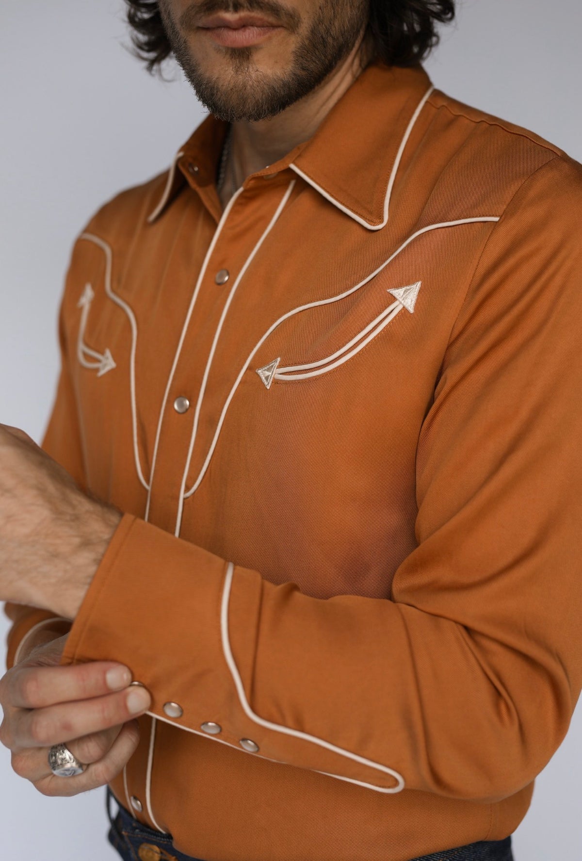 Close-up of the cream piping and embroidered arrow on the H Bar C San Fernando burnt orange Tencel shirt.