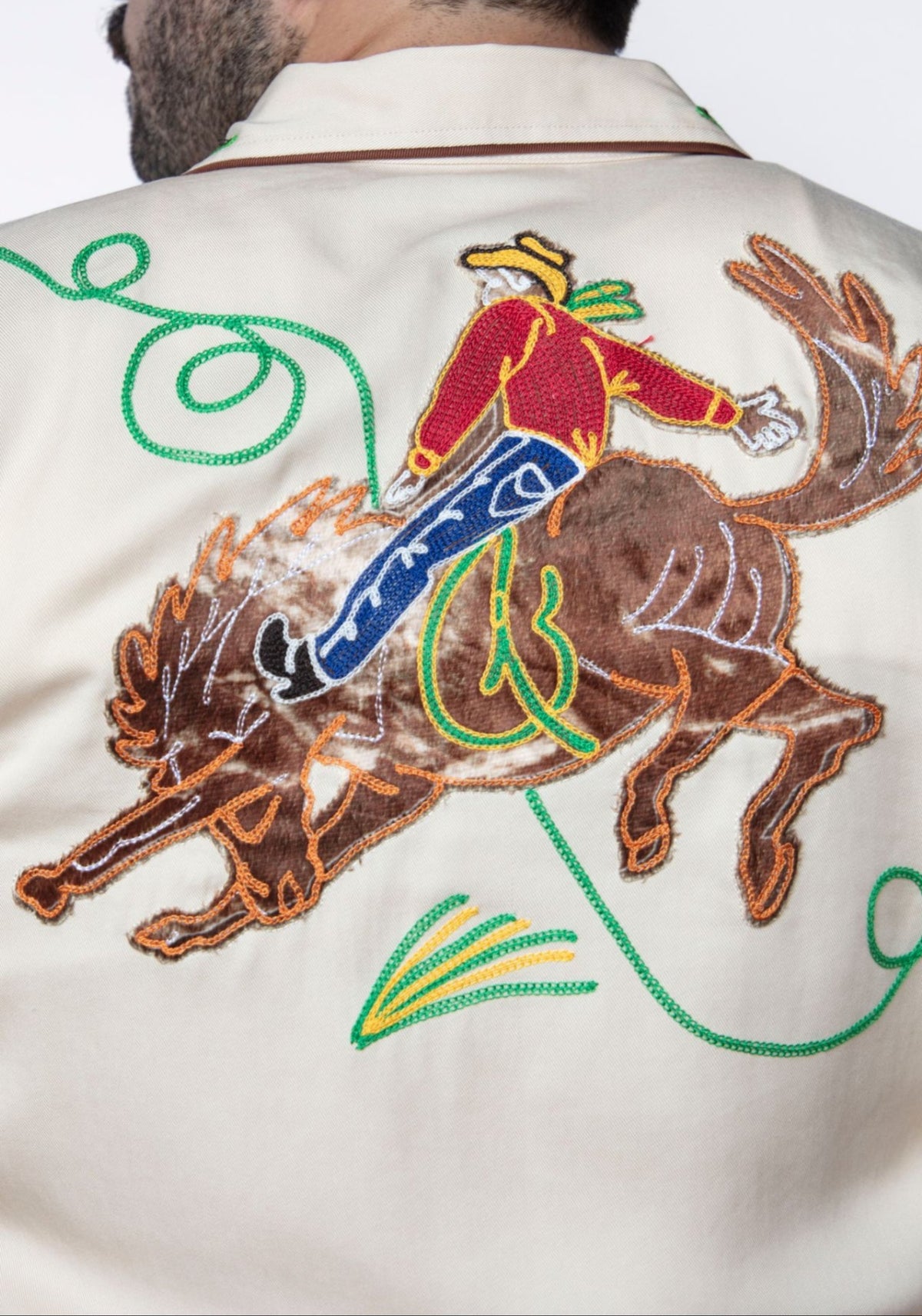 Back of the H Bar C Calabasas off-white shirt with a chain stitch embroidered cowboy riding a bucking bronco.