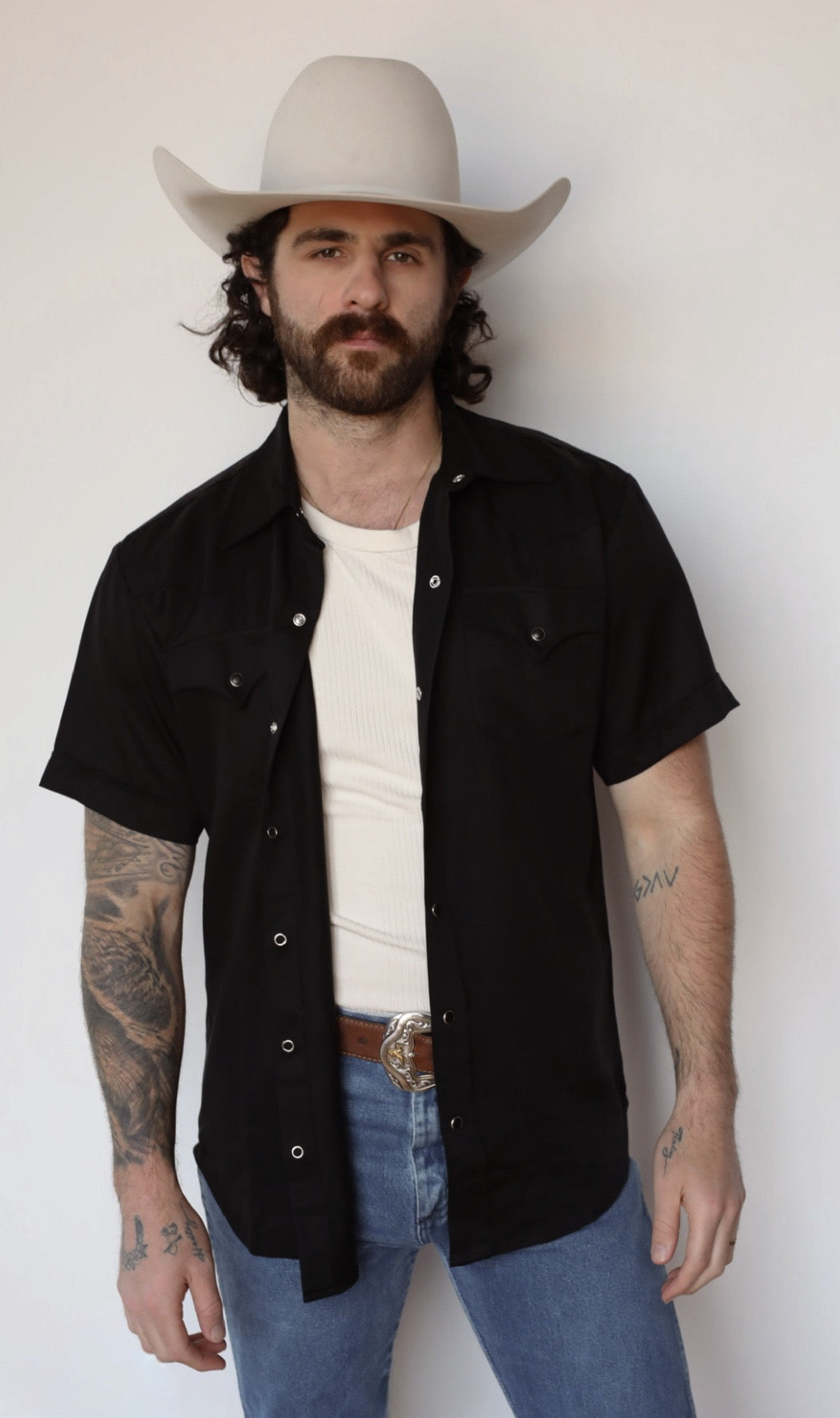 H Bar C Newport black short sleeve pearl snap shirt worn open over a white tee with jeans and a cowboy hat.