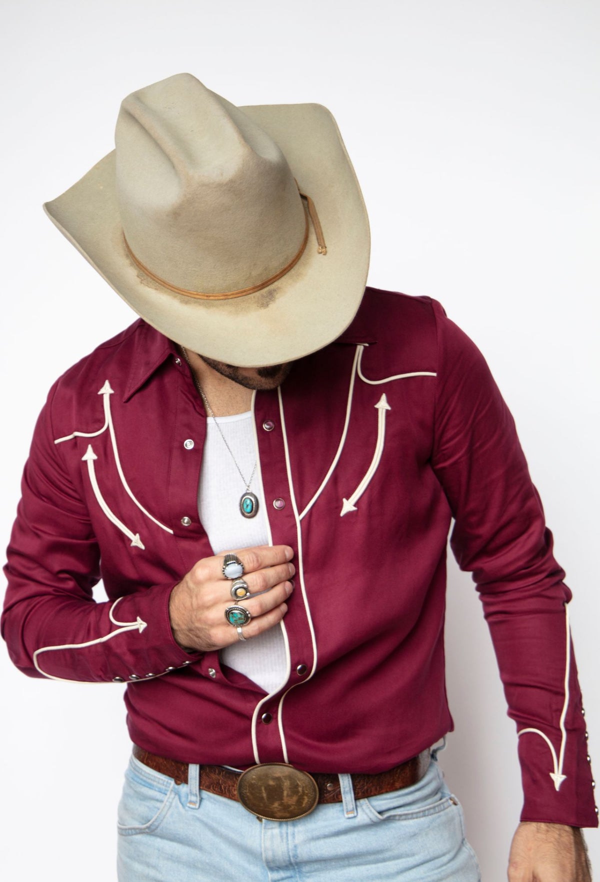 Man looking down in the H Bar C Reno maroon western shirt with off white piped yokes.