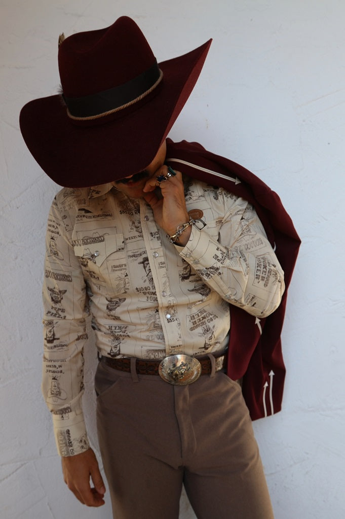 Man in a brown cowboy hat wearing the H Bar C Tumbleweed shirt in beige with a vintage western print, a 1970s H Bar C design.