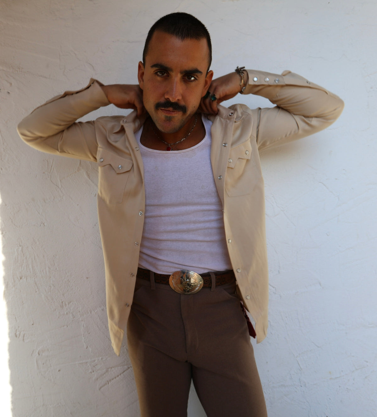 Man with hands behind his head wearing the H Bar C Kansas City beige western shirt over a white tank.