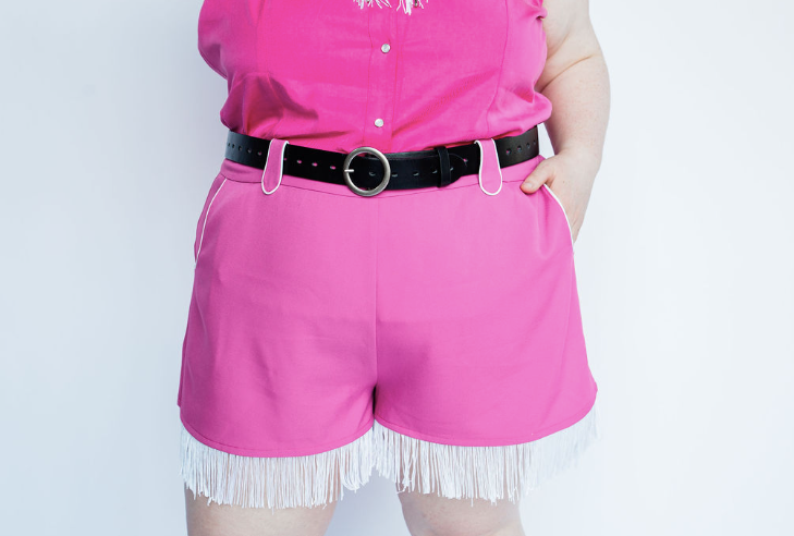 Close-up of the H Bar C Marfa pink shorts with white fringe hem, western belt loops and a black belt.