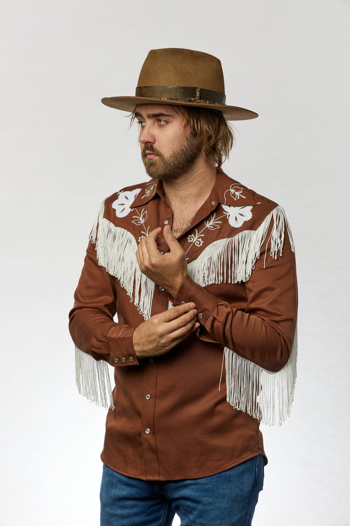 Man in a brown cowboy hat wearing the H Bar C Taos brown fringe western shirt with jeans.